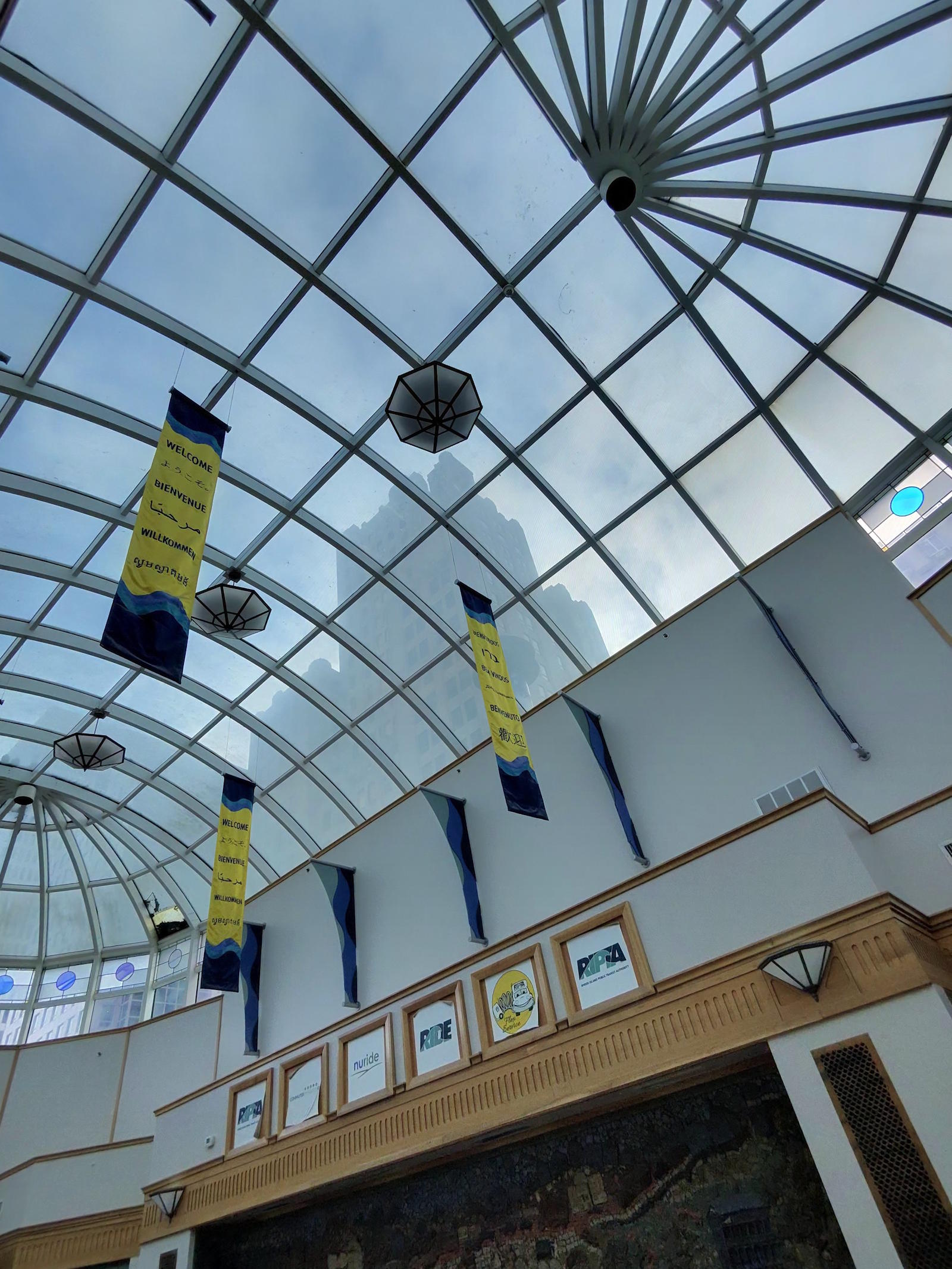 Kennedy Plaza Bus Terminal interior glass ceiling with Welcome banners in multiple languages, March 17, 2026